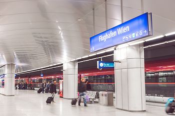 ÖBB Railjet im Flughafenbahnhof mit Reisenden im Vordergrund