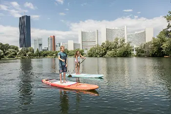 Zwei Personen stand up paddeling auf der Donau